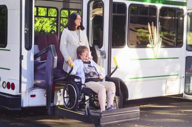 Woman helping a member out of a bus 